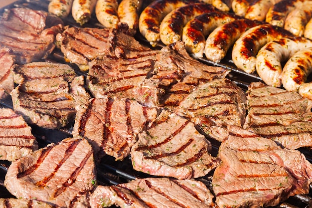 Meat steaks with sausages are grilled closeup