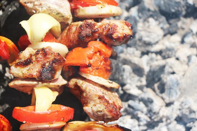 Meat and vegetables frying on a grill on a closeup background of the ash