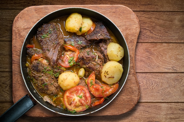 Meat with potatoes in iron pan