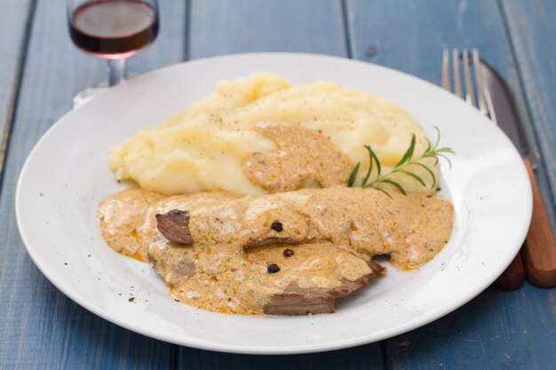 Meat with sauce and mashed potato on white plate