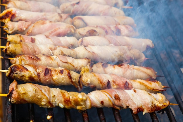 Meat wrapped in bacon on wooden skewers is grilled