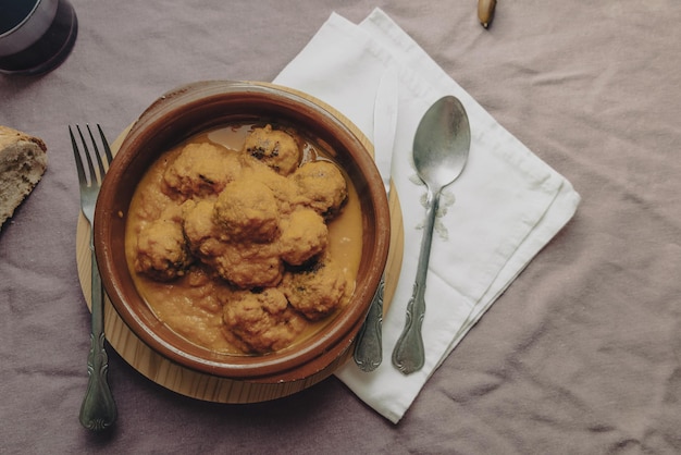 Meatball stew with tomato sauce in earthenware casserole dish.