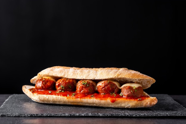 Meatball sub sandwich on black slate table