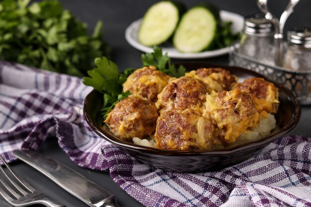 Meatballs in curry sauce in bowl against a dark background, horizontal orientation