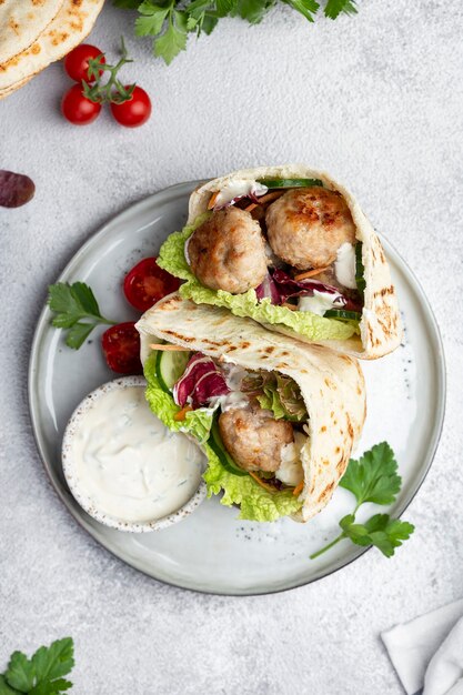 Meatballs in a pita with vegetable salad and yogurt sauce