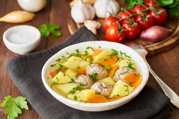 Minestra delle polpette in piatto bianco sulla vecchia tavola marrone rustica di legno, vista laterale