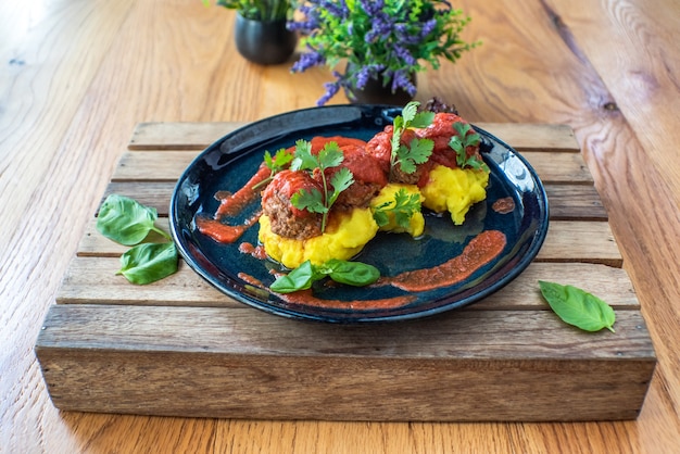 Meatballs in tomato sauce and mashed potato in a plate on wooden table