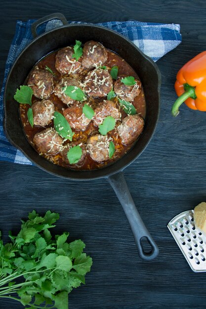 채소와 토마토 소스 미트볼입니다. 어두운 나무 배경입니다. 위에서 본