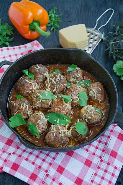 Meatballs in tomato sauce with greens. 