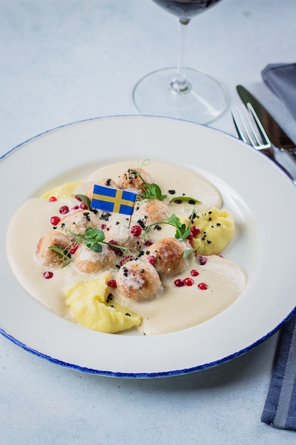 Meatballs with boiled potatoes, sauce and crunberry berry decorated by Swedish flag 