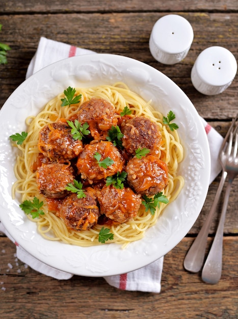 Foto polpette con riso, cipolle, carote con spaghetti in salsa di pomodoro. stile rustico, cibo rustico su un vecchio fondo di legno.