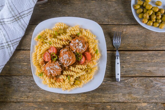 Meatballs with rotini pasta in white plate. Top view