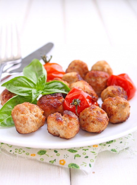 Foto polpette con pomodoro in un piatto bianco su uno sfondo bianco. messa a fuoco selettiva.