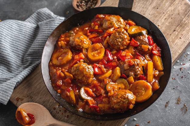 Meatballs with vegetables and sauce made in pan and served on table.