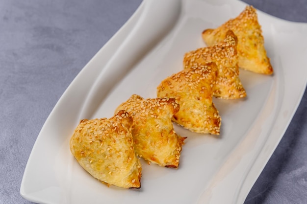 The meatballs wrapped in puff pastry covered with sesame seeds on a white plate