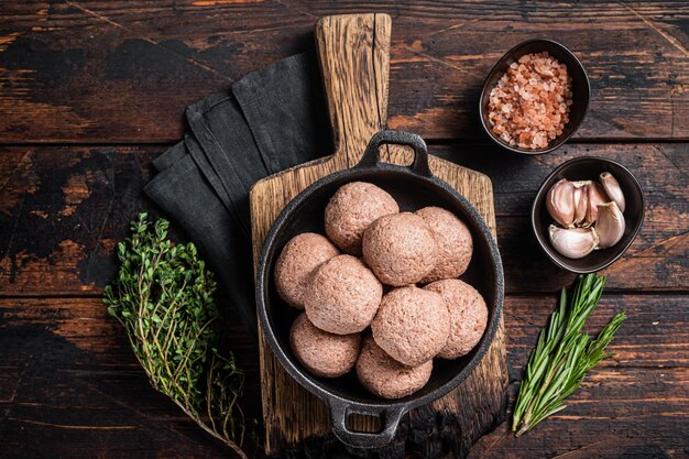 Photo meatless vegetarian meatballs from raw plant based meat with thyme and rosemary wooden background top view