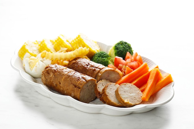 Meatloaf with mushroom glaze sliced on a plate ground beef and\
chicken dish served with steamed vegetable on white table