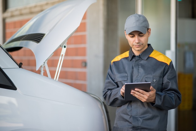 Photo mechainc using a tablet in front of a van