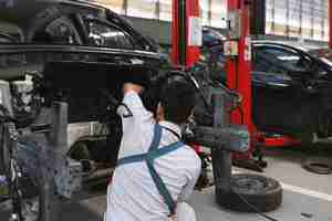 Photo mechanic assembling an engine block of a car in the garage room service