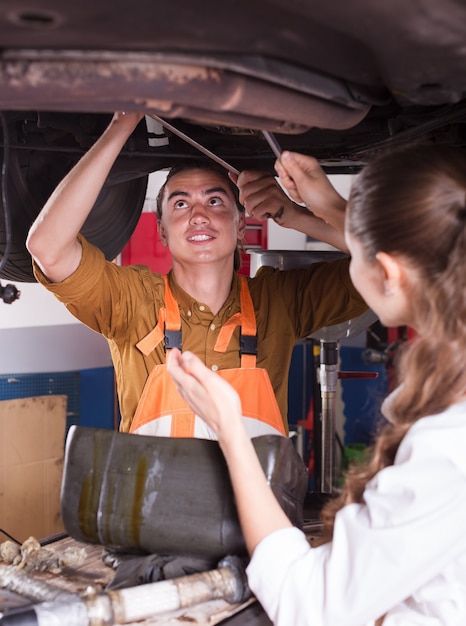 Mechanic and assistant working at workshop 