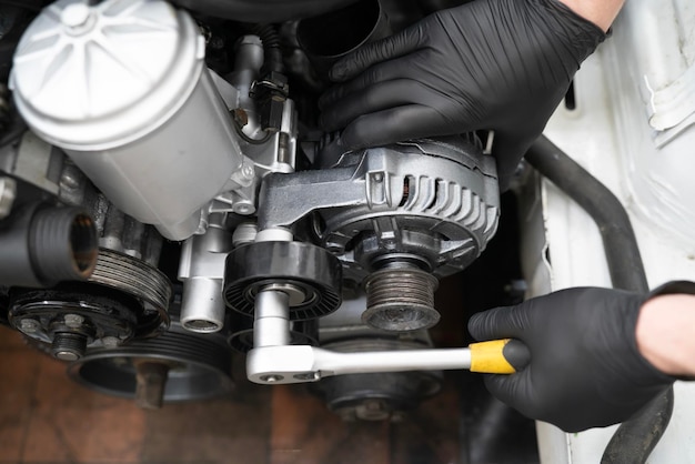 mechanic carefully installs a new pulley in an engine compartment during a repair session at an auto shop