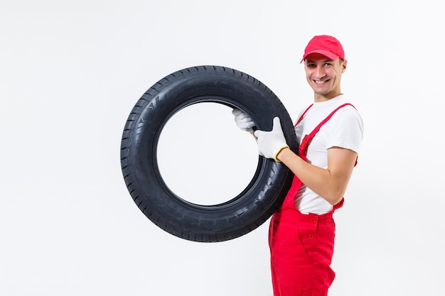 Mechanic carrying a tyre on a white background