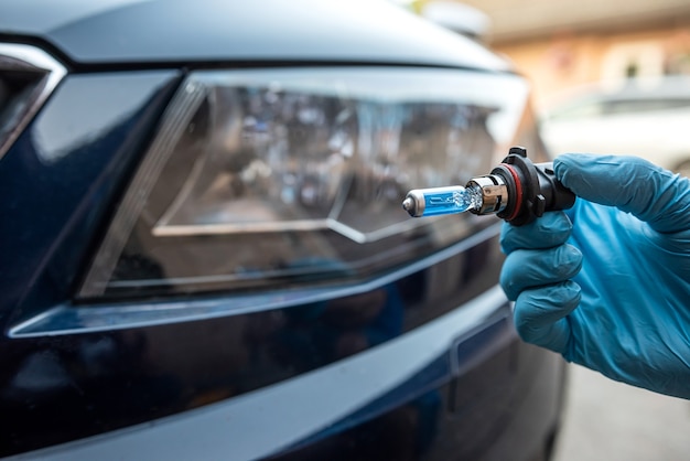 Mechanic changing car light bulb against headlight, auto service