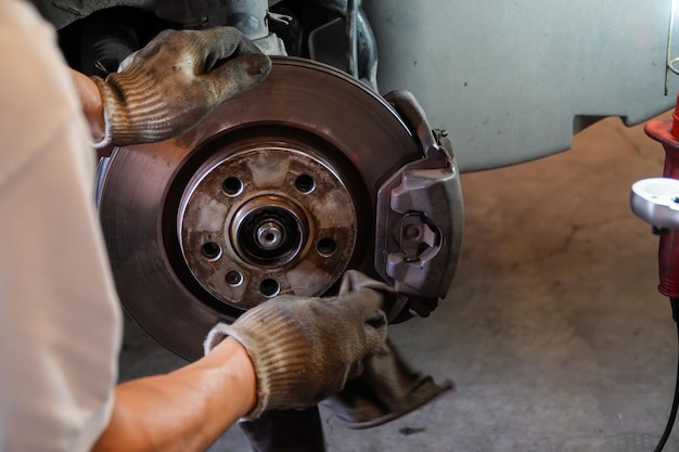 Mechanic checking car brake system and driveshaft in vintage garagecar garage service concept