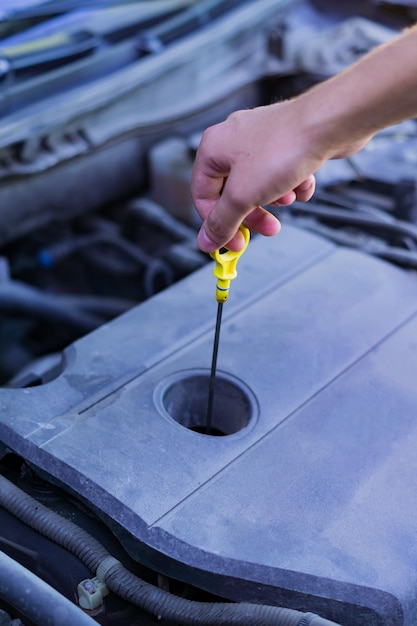 Foto meccanico che controlla e fissa una bacchetta di misurazione per controllare il livello di olio nel motore dell'auto