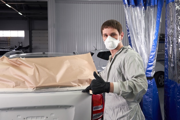 Mechanic covering car before painting in auto repair service