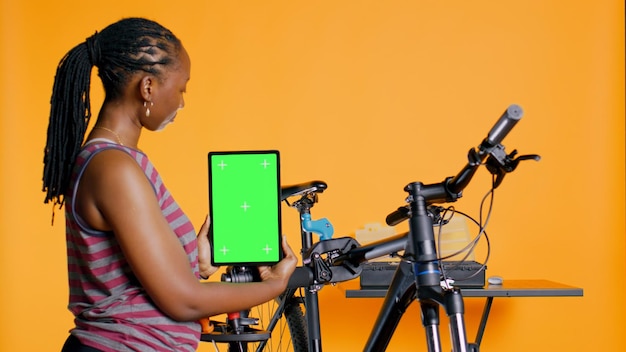 Mechanic die een fietsenreparatiedienst promoot met een mock-up tablet studio achtergrond