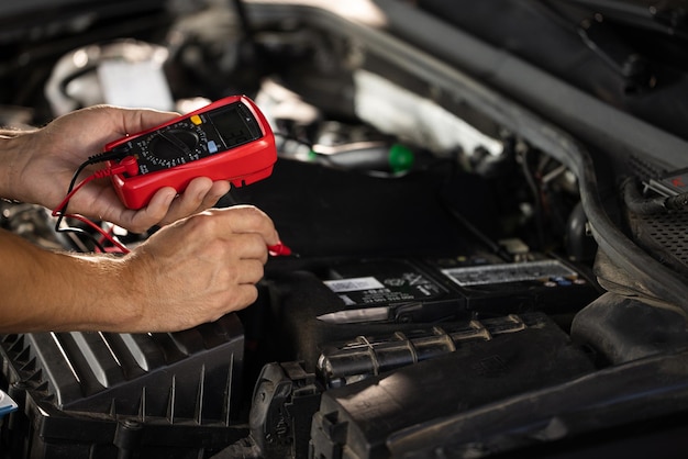 Mechanic doing car inspection he is testing car battery with tester check battery voltage