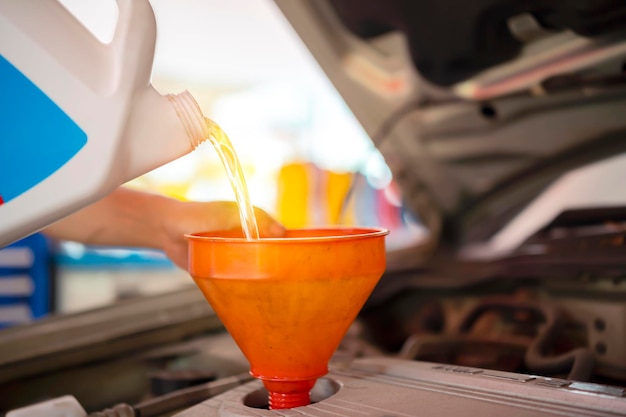 Mechanic draining engine oil from a car for an oil change at an auto shop