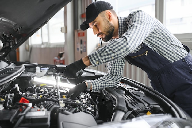 Mechanic examining under hood of car at the repair garage