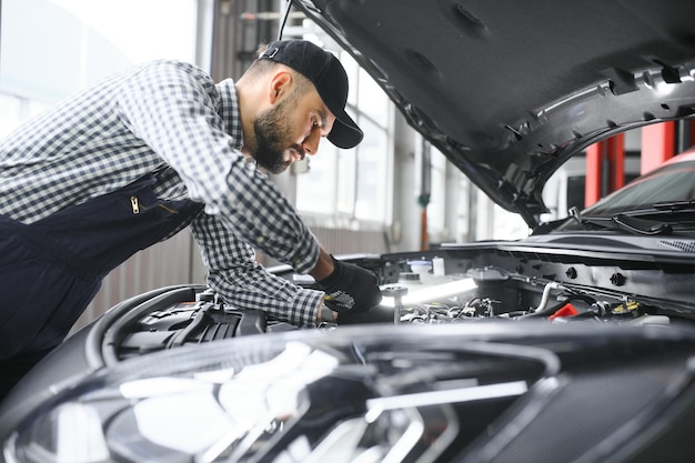 Mechanic examining under hood of car at the repair garage