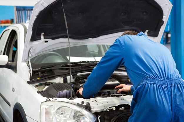 Mechanic examining under hood of car