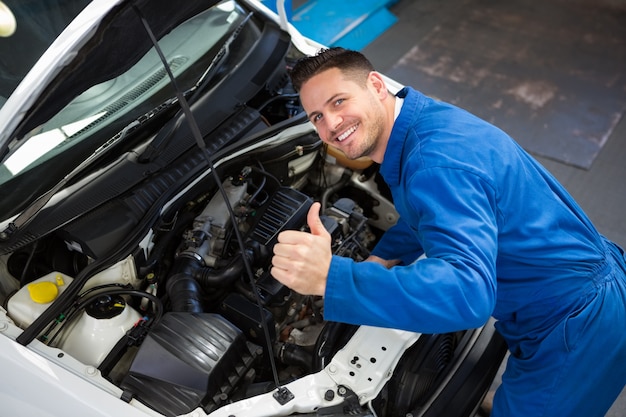 Mechanic examining under hood of car