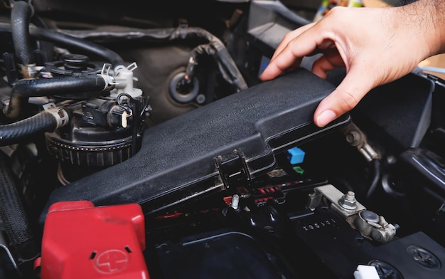 A mechanic hand is removing the fuse box from the automobile