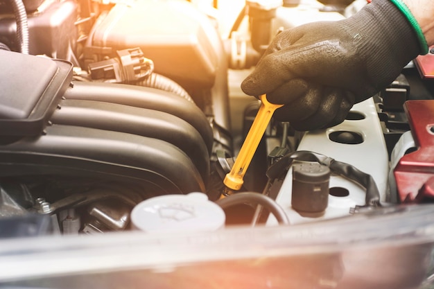 Mechanic hand was pulling oil dipstick to lube level checking of engine car