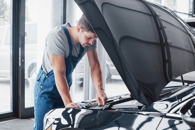 Mechanic hands checking up of serviceability of the car in open hood, close up.