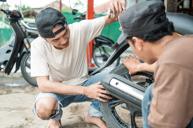 顧客がスクーターバイクを修理するのを助ける整備士