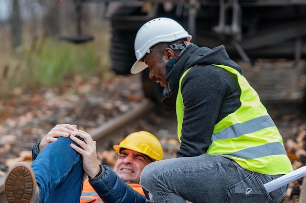 Mechanic helping injured colleague on railroad track