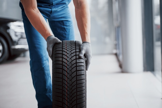 Mechanic holding a tire tire at the repair garage. replacement of winter and summer tires