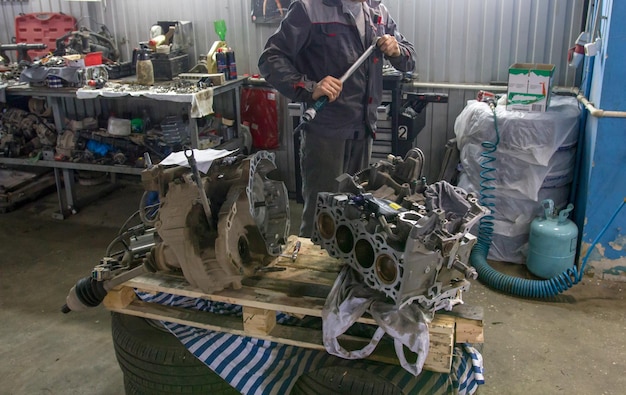 Mechanic holds the spanner while repairing the valve block of the car engine in the workshop