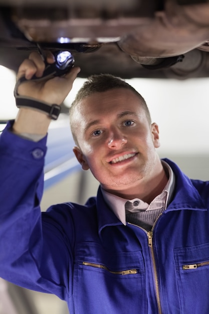 Mechanic illuminating the below of a car