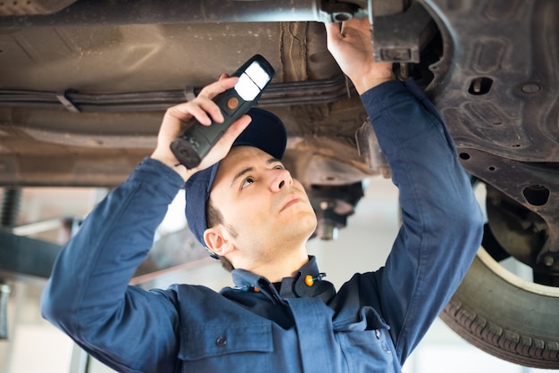 Photo mechanic inspecting a lifted car