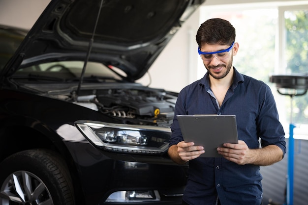 Mechanic inspects the car undercarriage way and makes a note on\
his inspection sheet automobile