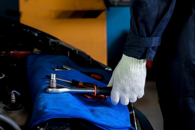 The mechanic is about to pick up the wrench to repair the car in the engine.