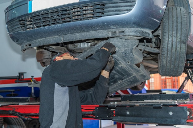 The mechanic is under the car to repair it