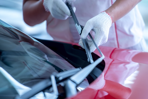 The mechanic is changing the wipers in the parking lot. Change the wiper tires to prepare for the windshield cleaning while raining during the rainy season.